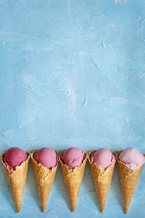 Fresh strawberry ice cream in waffle cone on blue background with copy space.の写真素材