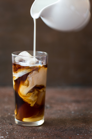 Iced cold brew coffee in a tall glass with cream poured overの写真素材