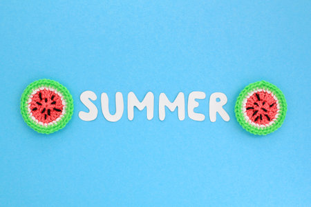 Colorful crochet handmade slices of watermelon and lettering Summer on blue background. Summertime vacation creative tropical bright minimal food concept. Flatlay, top view holiday compositionの写真素材