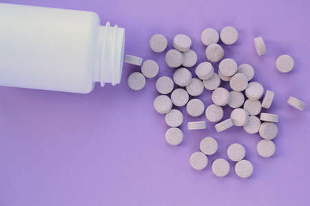 Tablets, capsule, pills and white plastic pack on purple background. Vitamin prescription...