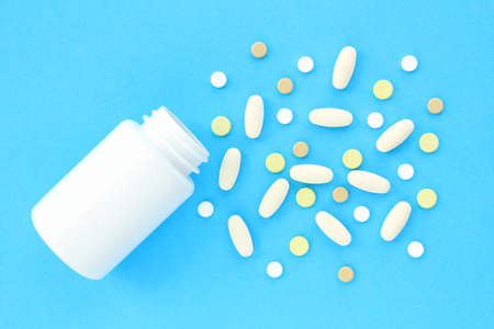 Tablets, capsule, pills and white plastic pack on blue background. Vitamin prescription supplement,...