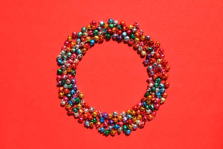 Little christmas colourful jingle bells round wreath on red background and copy space for text. Holiday festive happy new year concept. Greeting postcard, poster, banner. Mock upの写真素材