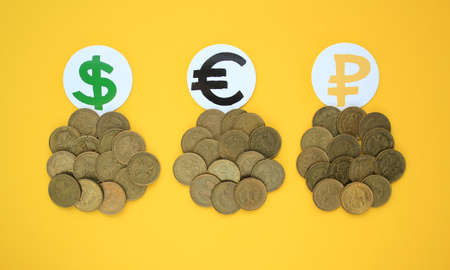 Coins and currency signs on yellow background. Diversification of currencies: dollar, euro, rouble. Saving money from inflation risks. Investment planning and control concept. Flatの写真素材