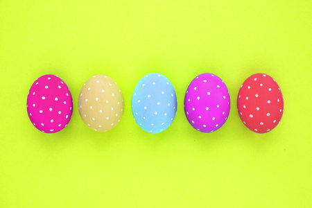 Easter colored eggs with polka dot on neon yellow background. Flatlay postcard creative concept. Isolated card decorated, poster, banner, web, magazine. Minimal idea with copy spaの写真素材