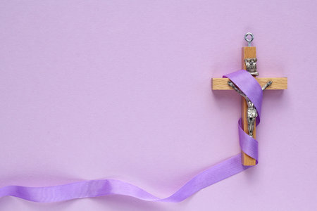 Wooden cross with a purple ribbon on a purple background. copyspace.の写真素材