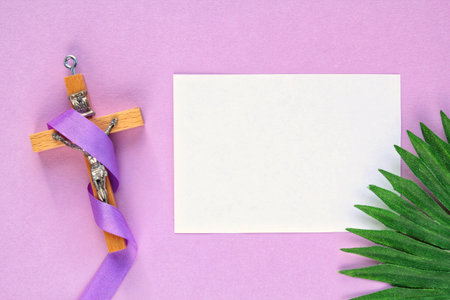 Wooden cross and blank paper on a purple background with palm leaf