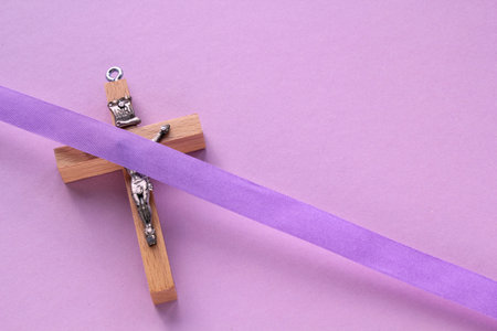 Christian religious wooden cross crucifix with violet ribbon on purple background. Catholic religion symbol. Good Friday, Lent Season, Palm Sunday, Ash Wednesday, Holy Week conceptの写真素材