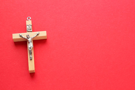 Crucifix christian wooden cross on red background. catholic symbol. Flat lay, top view, lay out, isolated. Pray for God, faith in Jesus Christ and believe religion conceptの写真素材