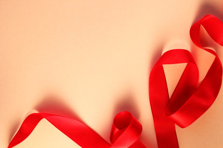 Red ribbon on a beige background. Copy space for text.の写真素材