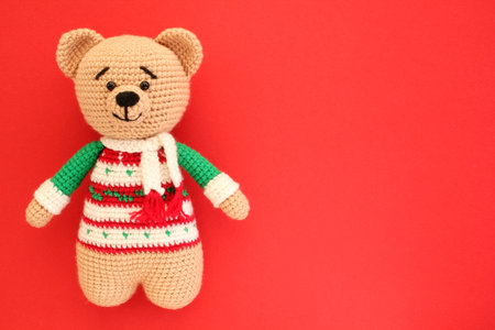 Handmade knitted toy bear on a red background. christmas concept.の写真素材