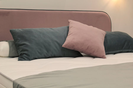 Close-up of comfortable colorful soft pillows on bed. Stylish trendy apartment home decor. Hygge...