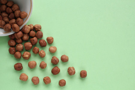 Hazelnut on white ceramic bowl on green background. Healthy eating diet, nutrition, vegan concept. protein organic food. Dry snack. national nut day. Copy space for textの写真素材