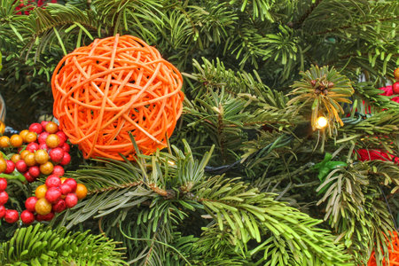 Colorful baubles and red rowanberries on spruce branch. Christmas tree decoration. Composition for winter holiday. Fir twigs with red berry and ballsの写真素材