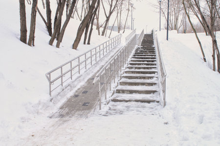 Stairs and ramp with metal railings for the passage of strollers and wheelchairs in public park at...