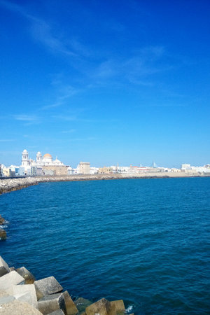 Cadiz embankment panorama with cathedral the Santa Cruz, big breakwater stones and Atlantic ocean. Seafront view of Cadiz. View of the promenade quay Andalusia region, Spainの写真素材