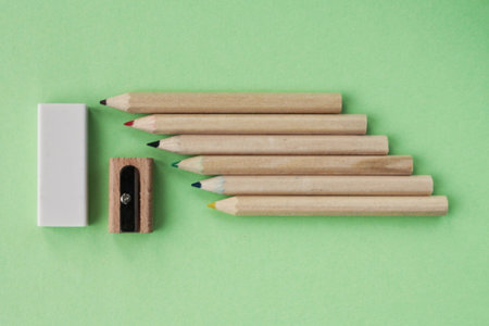 Colored pencils, wooden manual sharpener and eraser on green background. Back to school concept. Set of writing tools for education, creativity, drawing, hobby, art. Eco-friendly sの写真素材
