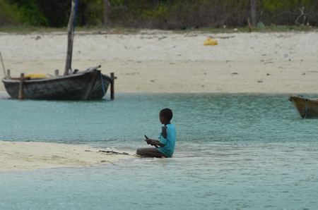 Zanzibar Tanzania Africa August 2016 African child waiting fishermen on Nungwi beachのeditorial素材