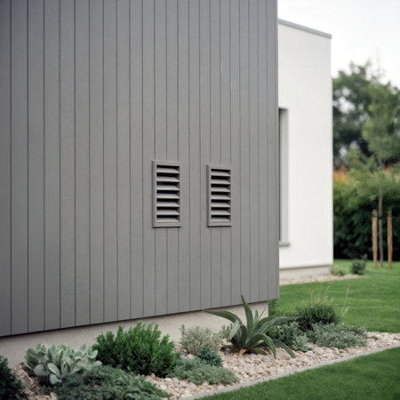 Two ventilation grilles on the gray paneled facade of a modern residential building.の素材