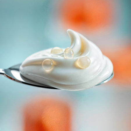 Spoonful of creamy yogurt with flavor pearls on a colorful background.の素材