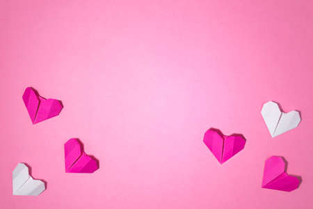 Pink background with pink and white origami hearts. High quality photo