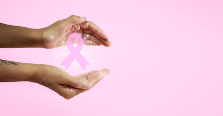 Banner with womans hands holding a pink ribbon for breast cancer awareness month. High quality photoの写真素材