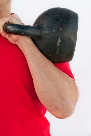 Strong man holding a Russian kettlebell on white background.の写真素材