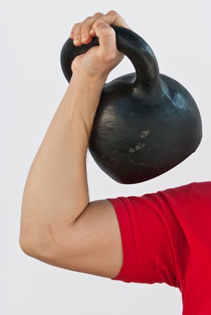 Strong man holding a Russian kettlebell on white background.の写真素材