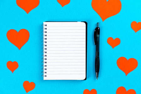 paper with pen on a blue background with red heartsの写真素材