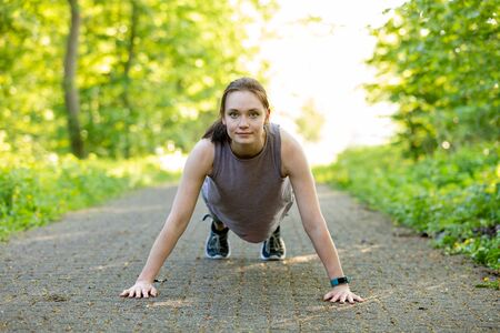 young woman makes fitness workout in nature