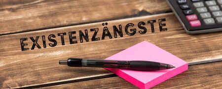 calculator with post it and pen with german text existenzÃ¤ngste, in english existence fears