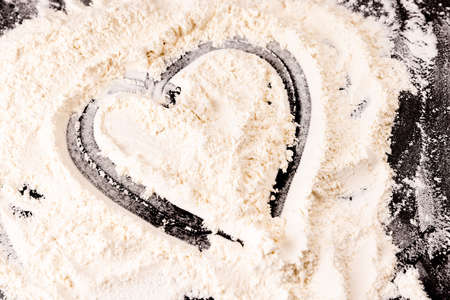 Heart of flour on a black background. Love and Valentine's Day concept.の写真素材
