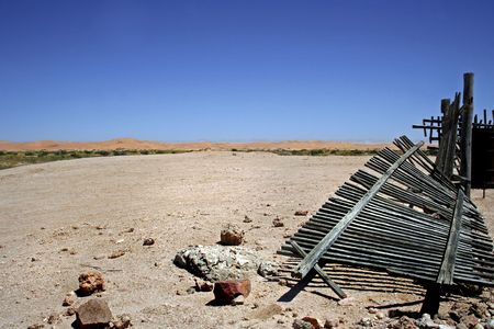 desert landscape with broken wooden picket fence in the foreground,dunes and blue sky in background in namibiaの写真素材