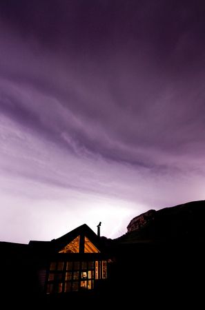 mountain cabin in foreground in thunderstorm with lightning lighting the mountain in the backgroundの写真素材