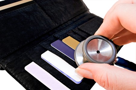 wallet with coins,notes and till slips being checked by stethoscope depicting concept of credit check or financial healthの写真素材