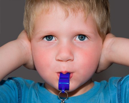 young toddler blond boy blowing blue whistle while hlding his ears shutの写真素材