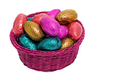 colorful easter eggs wrapped in shiny foil in wicker basket isolated on white background