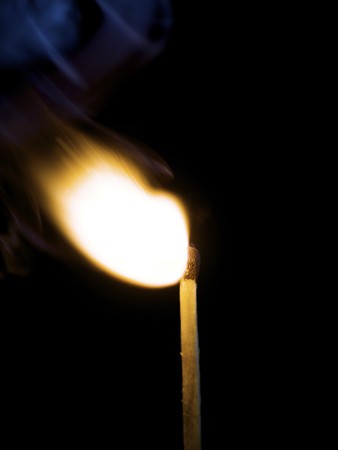 Wooden match burning on a black backgroundの写真素材