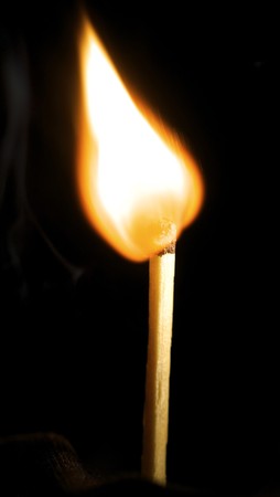 Wooden match burning on a black background