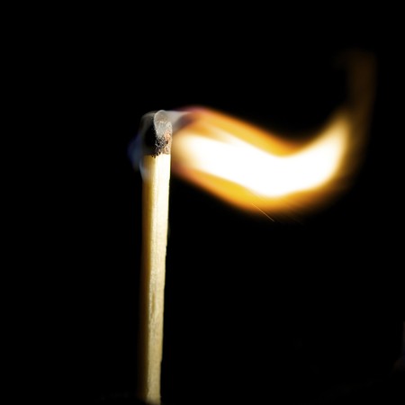 Wooden match burning on a black backgroundの写真素材