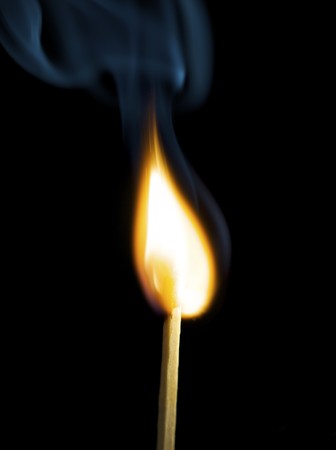 Wooden match burning on a black backgroundの写真素材