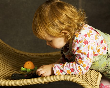 Small girl plays on the armchair
