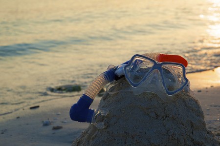 Snorkeling equipment (mask, snorkel and fins) on white sand beach with ocean on backgroundの写真素材