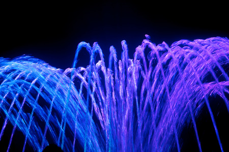 Colored water fountain at nightの写真素材