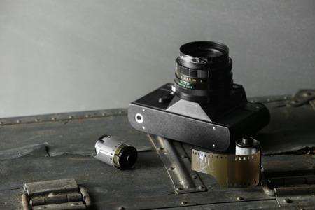 Old retro camera and 35 mm film in cartridge on a vintage background.の写真素材
