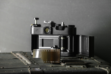 Old retro camera and 35 mm film in cartridge on a vintage background.の写真素材