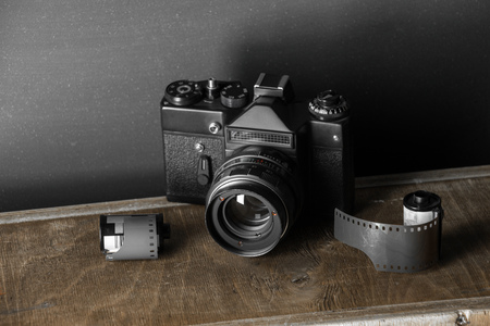 Old retro camera and 35 mm film in cartridge on a vintage background.の写真素材