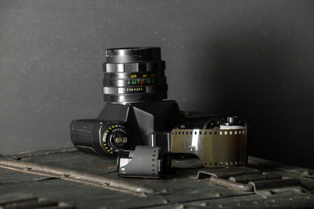 Old retro camera and 35 mm film in cartridge on a vintage background.の写真素材