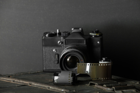 Old retro camera and 35 mm film in cartridge on a vintage background.の写真素材
