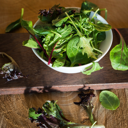 Vegetarian salad from a mix of fresh leaves in a plate on a wooden backgroundの写真素材