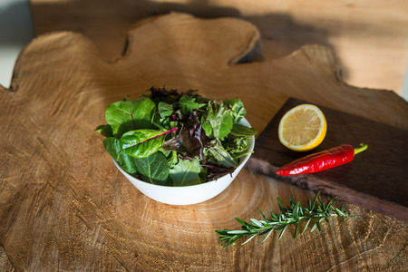 Vegetarian salad from a mix of fresh leaves in a plate on a wooden backgroundの写真素材